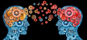 Teamwork and Leadership with education symbol represented by two human heads shaped with gears with red and gold brain idea made of  cogs representing the concept of intellectual communication through technology exchange.